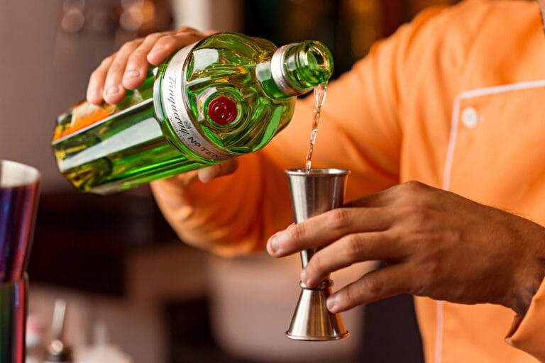 Barman nalewa gin do jiggera, przygotowując koktajl