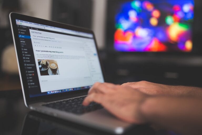 Osoba pisząca wpis na blogu WordPress na laptopie w przytulnym wnętrzu