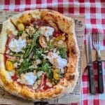 Pizza z rukolą, burratą i pomidorkami na kraciastej serwecie