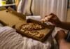 Mężczyzna je kawałek pizzy z pudełka w łóżku wieczorem