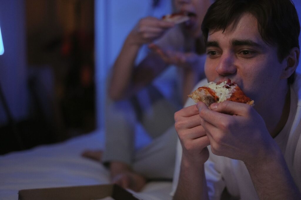 Grupa dorosłych je pizzę podczas wieczornego spotkania w lokalu