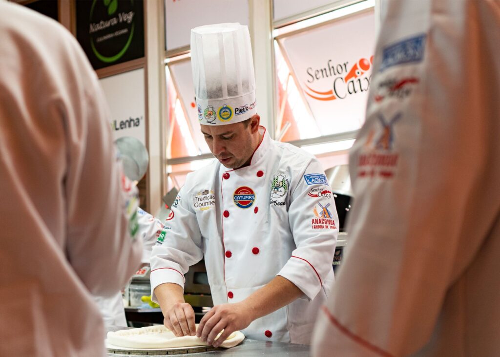 Pizzaiolo w czapce kucharskiej przygotowuje ciasto na pizzę gourmet